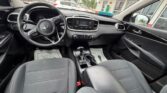 Interior of a Kia car: steering wheel, center touchscreen, climate controls, gear shifter, and front seating area visible in a clean cabin.