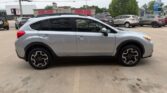 Side view of a silver crossover SUV parked in a lot, showing black alloy wheels and roof rails with other cars in the background