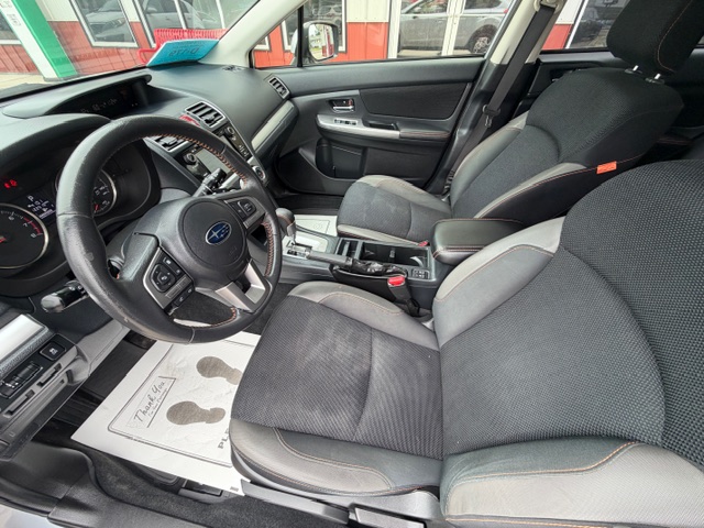 Front interior of a Subaru SUV: driver and passenger seats, steering wheel with badge, and center console; floor mat reads 'Thank you'.