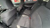Rear interior of a car with black fabric seats, three seating positions, and floor mats visible beneath them.