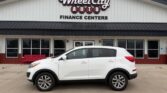 White SUV parked in front of Wheel City Auto Finance Centers storefront signage at a dealership.