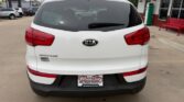 Rear view of a white Kia Sorento SUV at a car dealership, showing red taillights and a Wheel City license plate frame.