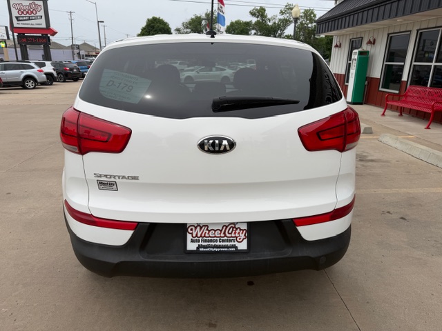 Rear view of a white Kia Sorento SUV at a car dealership, showing red taillights and a Wheel City license plate frame.