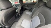 Rear seating area of a sedan with black/gray cloth seats, three headrests, and visible seat belts. Front seats and floor mats also visible.