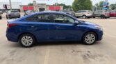 Blue two-door sedan seen in a car dealership lot, side profile facing left.