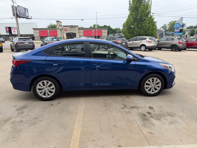 Blue two-door sedan seen in a car dealership lot, side profile facing left.