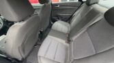 Rear passenger seating in a gray cloth interior with three seat belts and headrests, view from the backseat area of a sedan with front seats nearby.