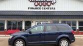 Blue SUV parked in front of Wheel City Auto Finance Centers storefronts/signs on a sunny day.