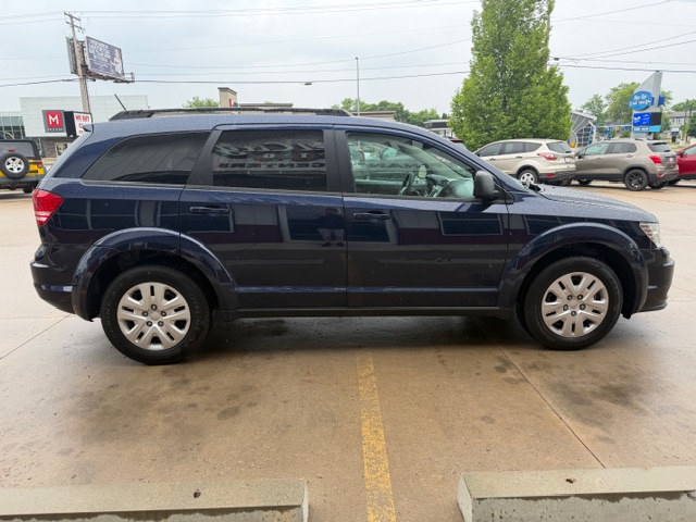 Side view of a dark-blue SUV parked in a parking lot with other cars in the background.