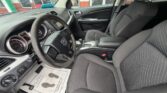 Front interior of a car showing the steering wheel, dashboard, and two gray fabric seats.