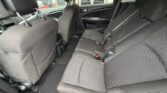 Interior of a car's back seat area with black fabric seats and three seating positions, visible seat belts, and front seats nearby