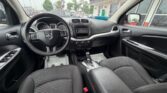 Front interior of a black Dodge sedan: steering wheel, center console with touchscreen, gear shifter, and front seats the dashboard visible through the windshield.
