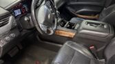 Front interior of a Chevrolet SUV showing black leather seats, steering wheel, center console, and wood-trim dashboard accents.