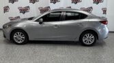 Side profile of a silver sedan parked indoors with a backdrop displaying Wheel City Auto Finance Centers logos