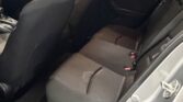 Interior of a car's back seat area with black fabric seats, two headrests, and visible seat belts; photo taken from the open rear passenger door.