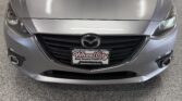 Front view of a silver Mazda car in a dealership showroom with Wheel City Auto Financing Centers backdrop