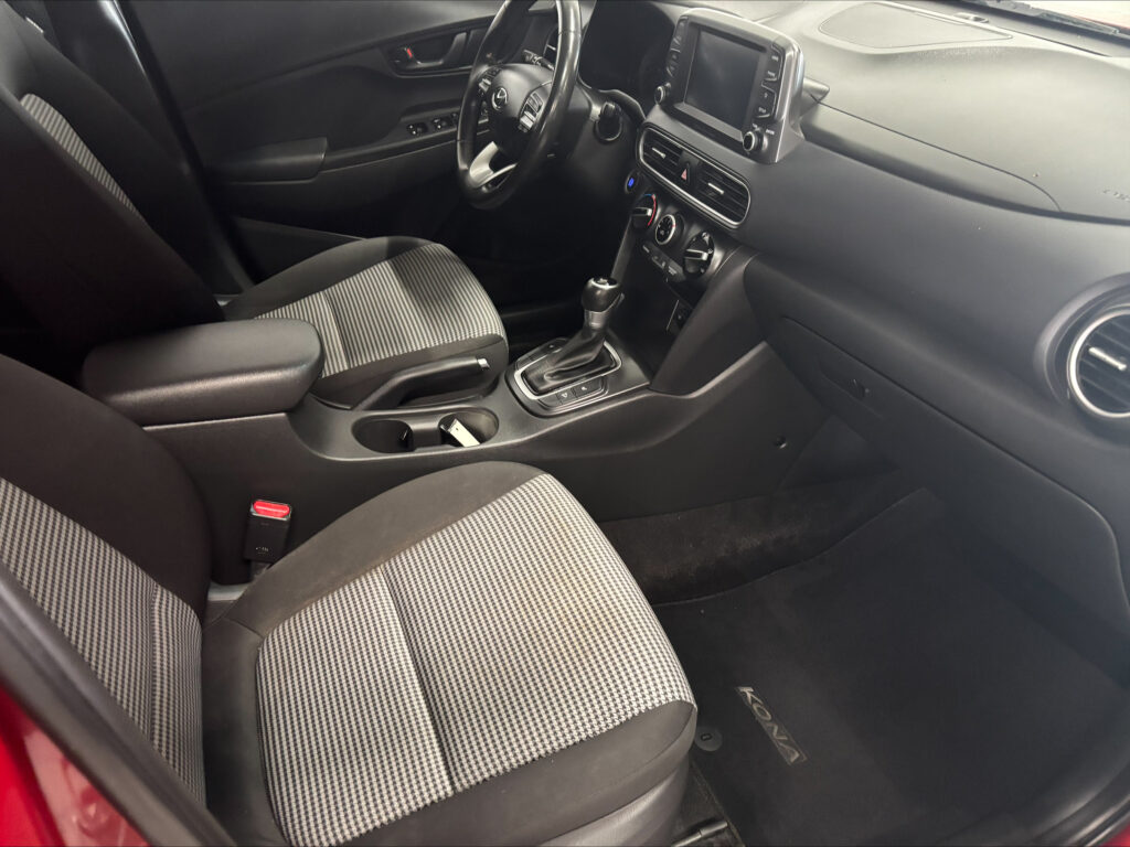 Front interior of a car: driver and passenger seats, center console with gear shifter and touchscreen display.