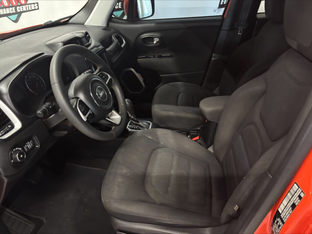 Interior of a modern car from the driver’s side, showing the steering wheel, dashboard, center console, and front passenger seat