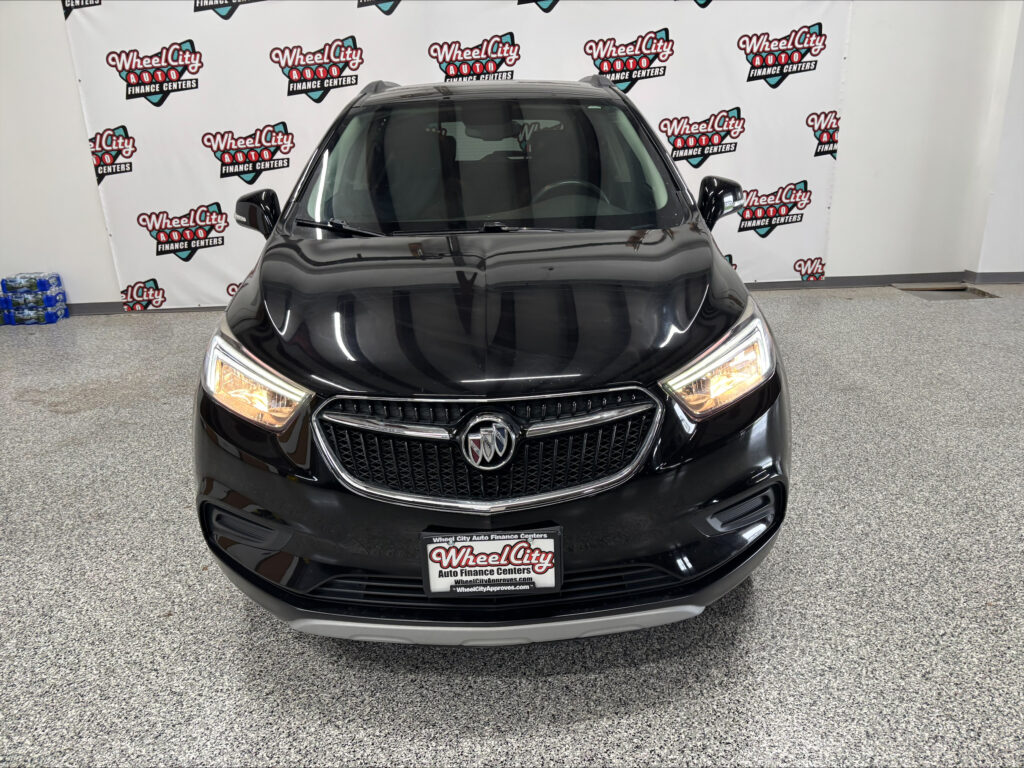Front view of a black Buick SUV in a showroom with Wheel City Auto Finance Centers banners in the background.