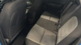Rear passenger seat area of a car with black fabric and gray patterned upholstery, visible seat belts and door panel on the right side.