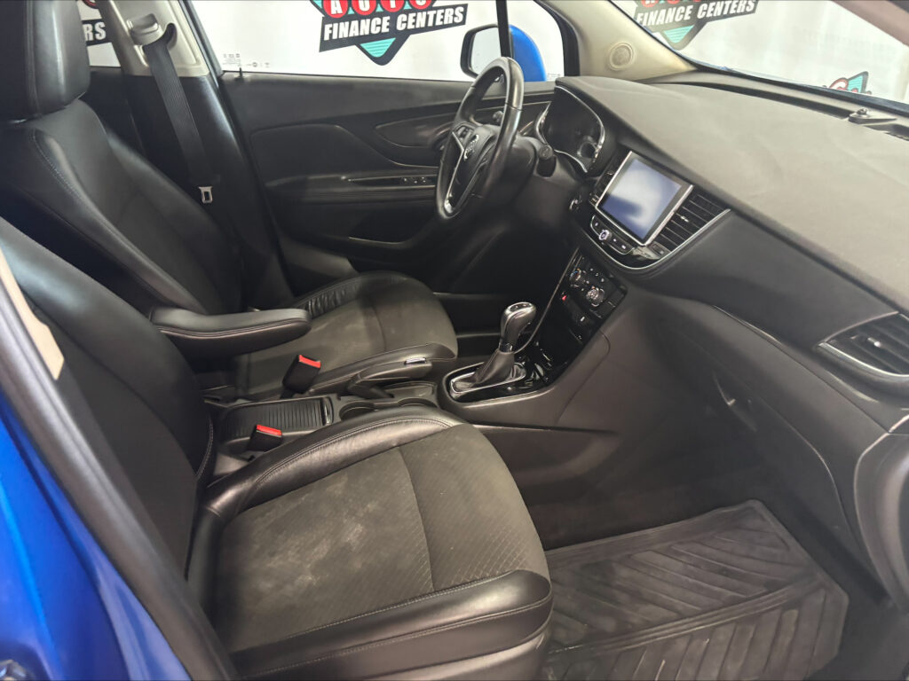 Driver’s area of a black leather car interior: steering wheel, center touchscreen, and gear shifter visible.