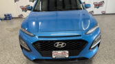 Front view of a blue Hyundai SUV in a showroom with branded backdrop reading Wheel City Auto Finance Centers.