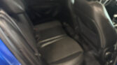 Blurry view of a car's dark interior seen through an open door, with black seats and dashboard in soft focus.