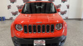 Front view of a red Jeep SUV in a showroom with Wheel City Auto Finance Centers banners in the background.