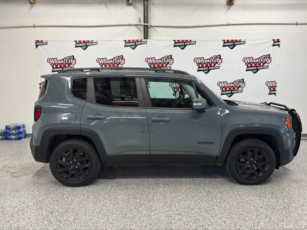 Gray SUV in a showroom with a Wheel City Auto banner backdrop, roof rails visible on top, and black wheels in the foreground.