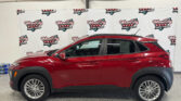 Red SUV indoors in front of a Wheel City Auto Finance Centers backdrop banner.