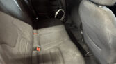 Rear passenger area of a car with gray cloth seats, red seat belt latches, and a speaker on the door panel
