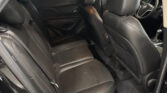 Back seat area of a black leather car interior, with front seats visible and a portion of the steering wheel in view.