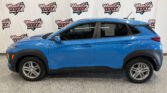 Blue SUV parked indoors in front of a Wheel City Auto Finance Centers backdrop with a side view and window sticker visible on the rear door panel.