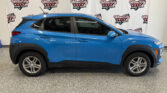 Blue SUV parked indoors in front of a Wheel City Auto Finance Centers banner backdrop on a showroom wall.