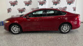 Red sedan displayed indoors against a backdrop of Wheel City Auto Finance Centers banners, showing the car's side profile.
