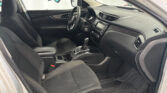 Interior of a sedan showing the front seats, steering wheel, center console with a touchscreen, and floor mats, all in dark fabric upholstery.