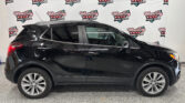Side view of a black SUV parked indoors with a Wheel City Auto backdrop in the background showing logos and branding.