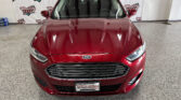 Front view of a red Ford car in a showroom with Wheel City Auto Finance Centers backdrop behind it.