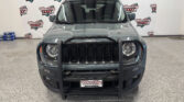 Front view of a gray Jeep Wrangler in a showroom, with a Wheel City Auto Finance Centers backdrop behind it.