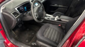 Interior of a red car showing the driver’s seat, steering wheel, and center console with a digital display screen.