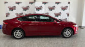 Red sedan parked indoors in front of a white wall banner that reads Wheel City Auto Finance Centers repeatedly.