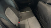 Rear car seat with black and gray checkered upholstery and visible red seat belt buckles, viewed from the left side.