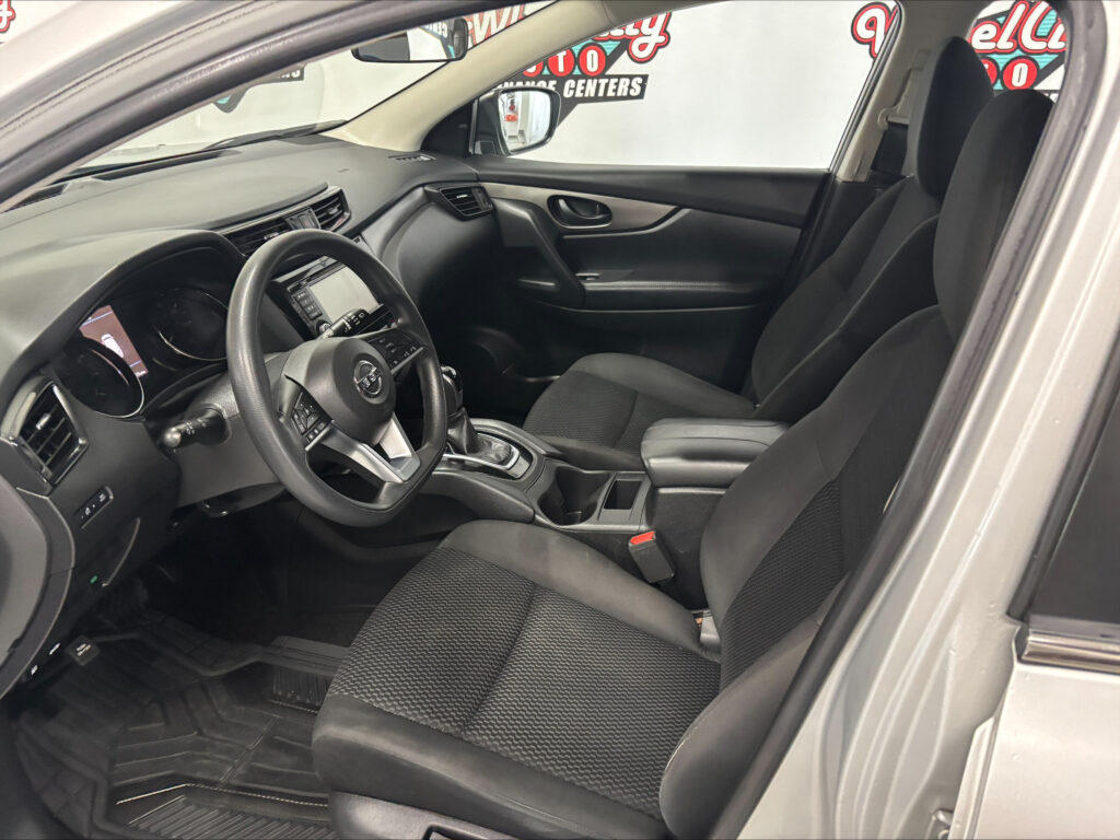 Inside view of a car cabin featuring the driver’s seat and front passenger seat, steering wheel, center console, and touchscreen display.