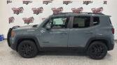 Gray Jeep Renegade SUV parked indoors in front of a Wheel City Auto Finance Centers banner backdrop.