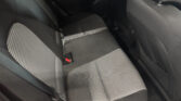Interior of a car backseat with gray patterned fabric seats and visible seat belts on the left and middle seats