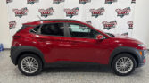 Red SUV parked indoors in front of a white banner with Wheel City Auto Finance Centers logos.
