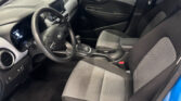 Interior view of a car's front cabin: steering wheel, dashboard, center console, and gray checkered seats with a gear shifter visible