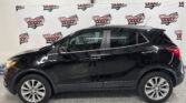 Black SUV indoors beside a banner reading Wheel City Auto Finance Centers on a white backdrop, showroom setting.