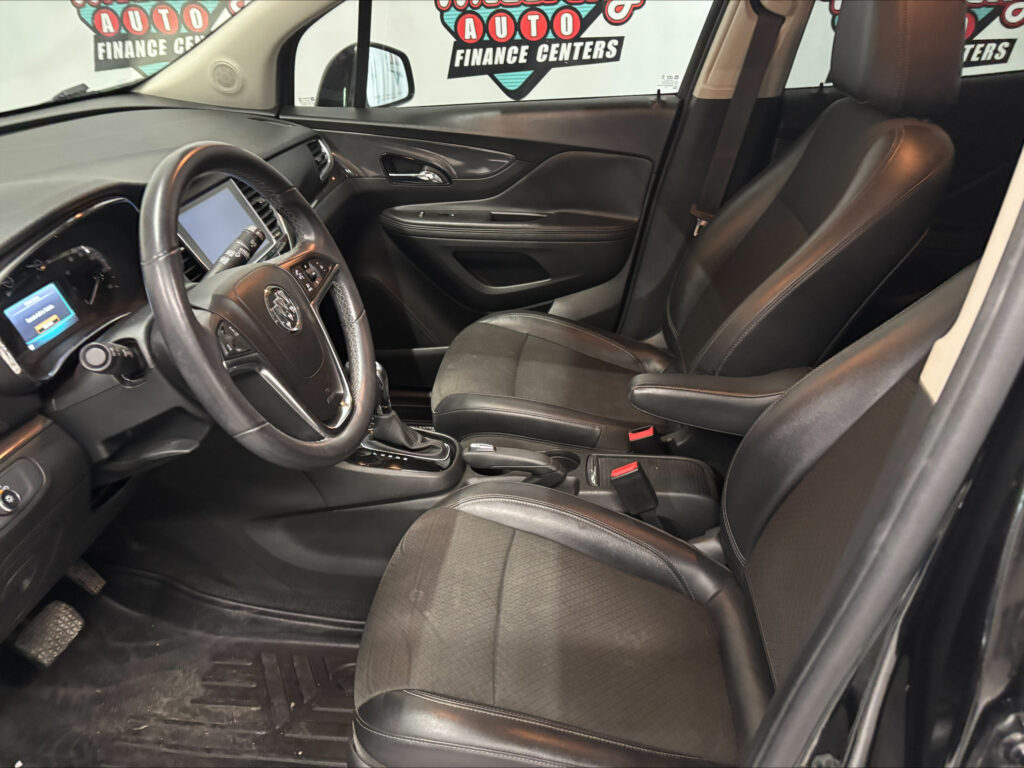 Car interior focusing on the front seats, steering wheel, and center console with black leather upholstery.