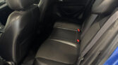 Rear passenger seat area of a car with black leather upholstery and visible stitching.